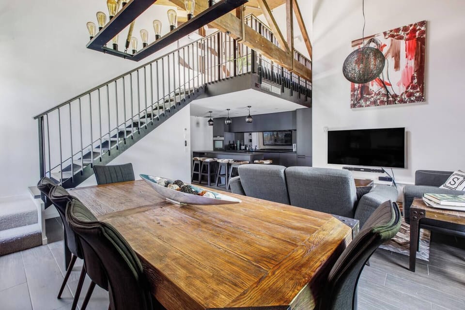 The apartment gives off a majestic vibe with soaring ceilings and a grand staircase leading up to the second level.

