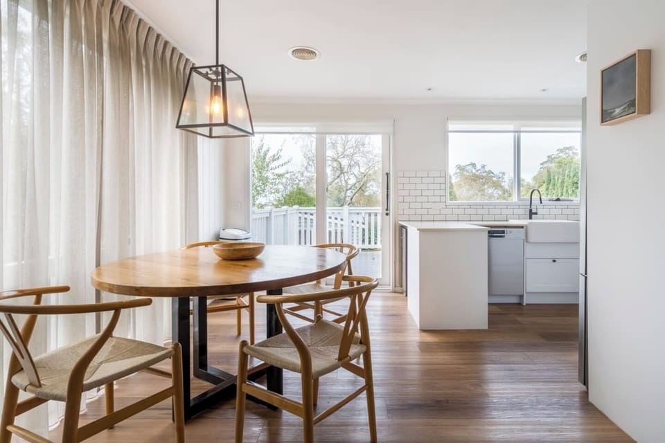 Share meals at the timber dining table overlooking the rear deck, where light streams in and the outdoors feels just a step away.