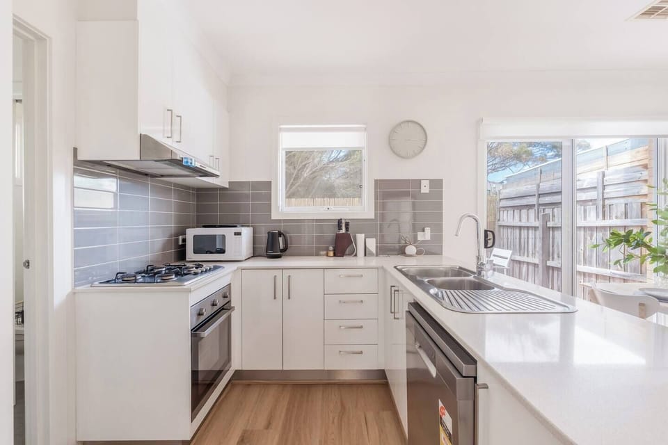 The kitchen provides a streamlined cooking zone with modern appliances, full cookware, dishwasher, kettle, toaster and spacious benches that make meal preparation smooth and intuitive.