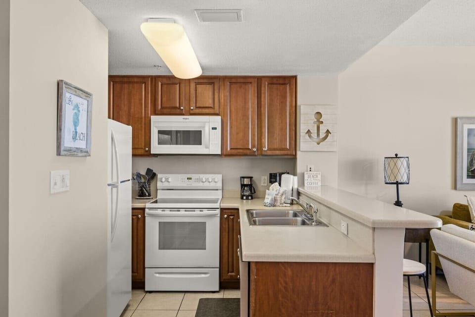 Prepare meals in the full kitchen featuring warm wood cabinetry, white appliances, generous counter space, and an open layout.