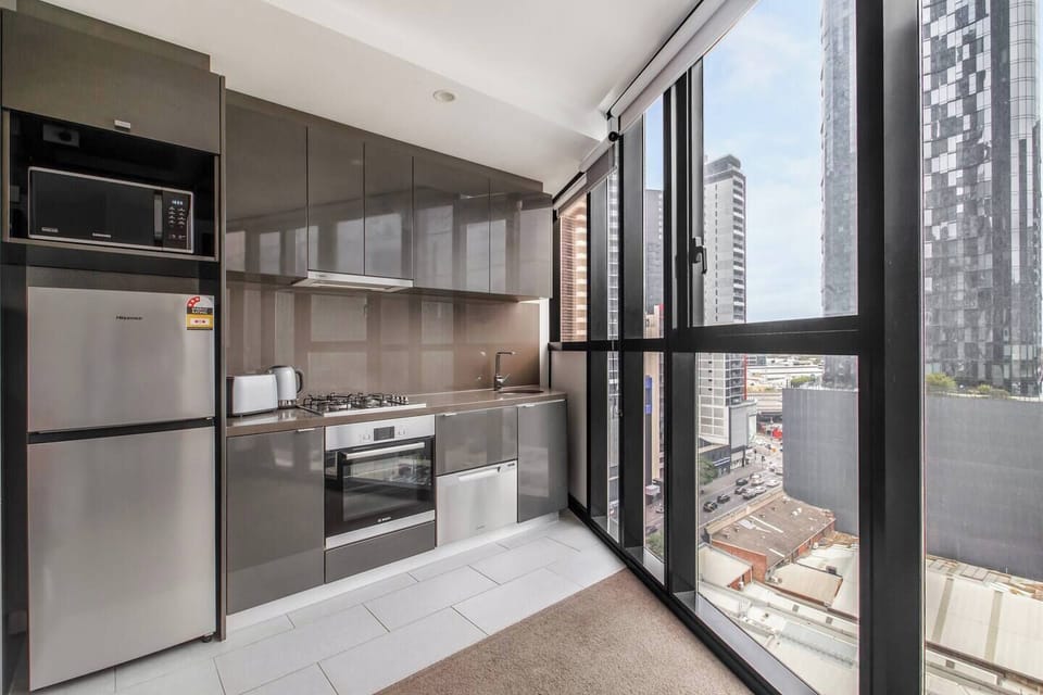 Prepare quick meals in the compact yet efficient kitchen, featuring the modern oven, gas stove, and full-sized fridge, all while soaking in expansive urban views.