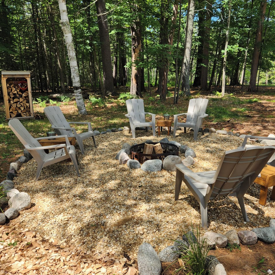 Fire pit by cottage with chairs, tables and wood provided.