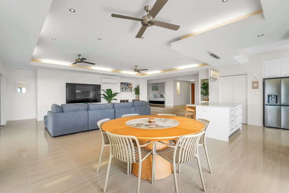 Gather around the spacious dining table, where leafy surrounds and the open-plan layout create an inviting setting for lingering meals together.