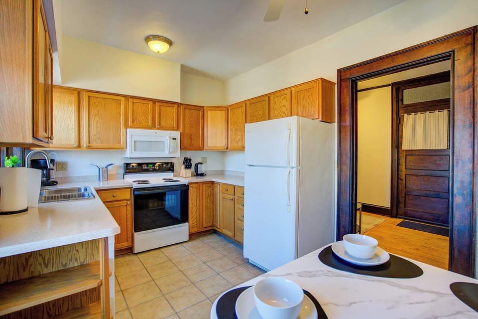 This kitchen is bright and functional, featuring warm wood cabinetry, durable countertops, and full-size appliances for easy meal prep. The layout is both practical and welcoming, with ample storage and all the essentials you need to cook comfortably