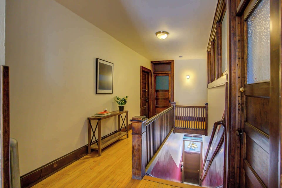 Welcoming entryway with a classic wooden staircase leading up to the unit. Thoughtful touches like a console table, books, and greenery create a warm, home-like atmosphere right from the entrance.