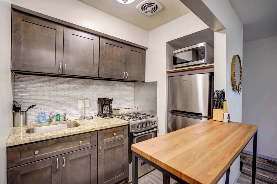 Modern kitchen equipped with stainless steel appliances, a gas range, and a butcher block island—perfect for cooking or enjoying a quick meal in a cozy, well-lit space.