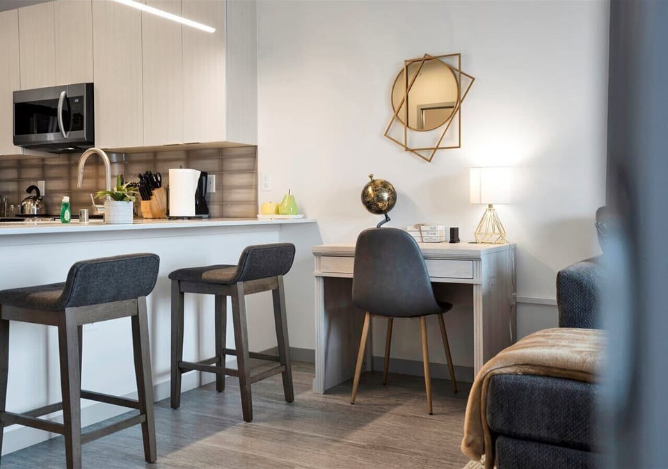 Modern kitchen bar with seating for two and a cozy desk nook. Warm lighting, sleek cabinetry, and stylish décor create an inviting space for dining or working.