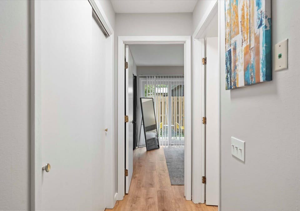 Bright hallway with modern artwork and wood-style flooring, offering a clean transition between the living space and the bedroom with private patio access.