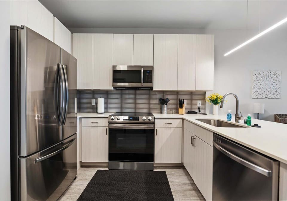 Modern kitchen featuring stainless steel appliances, ample cabinet space with open shelving, and a sleek tile backsplash—perfect for cooking and entertaining.