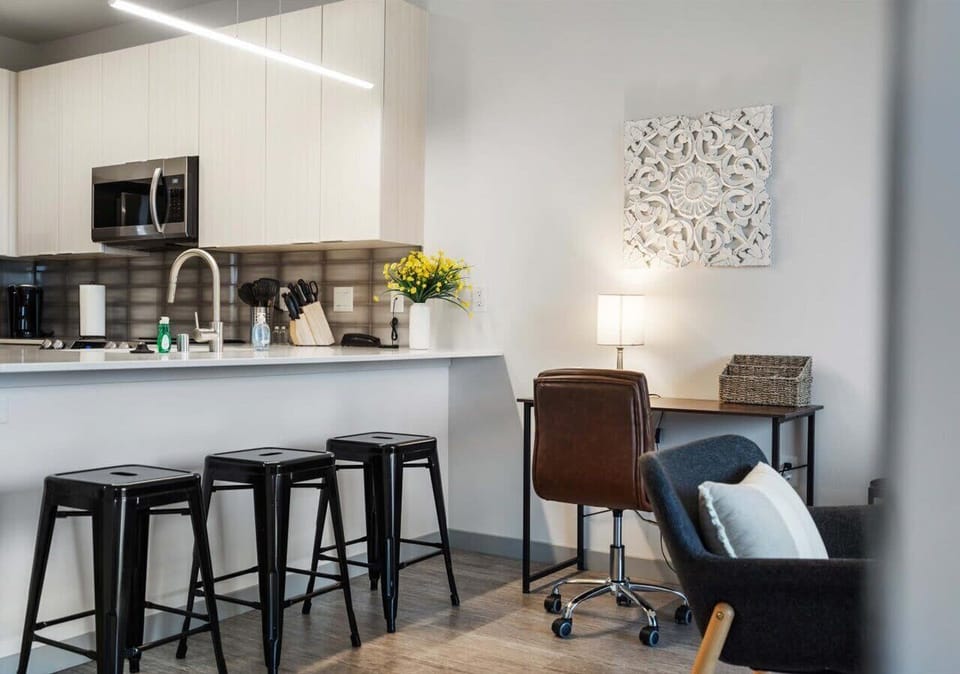 Stylish open-concept space with a kitchen island featuring bar seating, complemented by a cozy desk setup and modern decor. Perfect balance of functionality and comfort for dining, working, or relaxing.