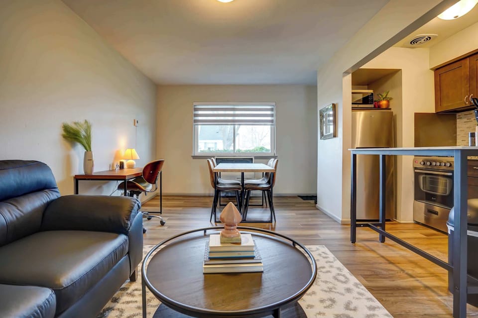 Open living area with a cozy sectional, dedicated workspace, and dining table for four—perfect for working, dining, or relaxing in comfort.