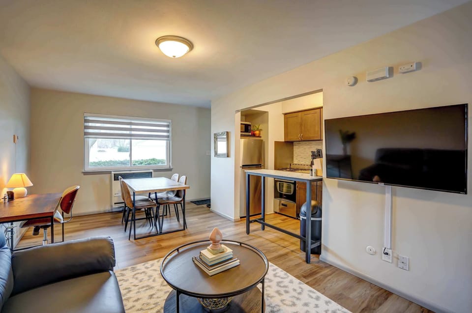 Spacious living area with a plush sectional sofa, 65" Roku Smart TV, and dedicated workspace—perfect for relaxing, streaming your favorite shows, or catching up on work in comfort.
