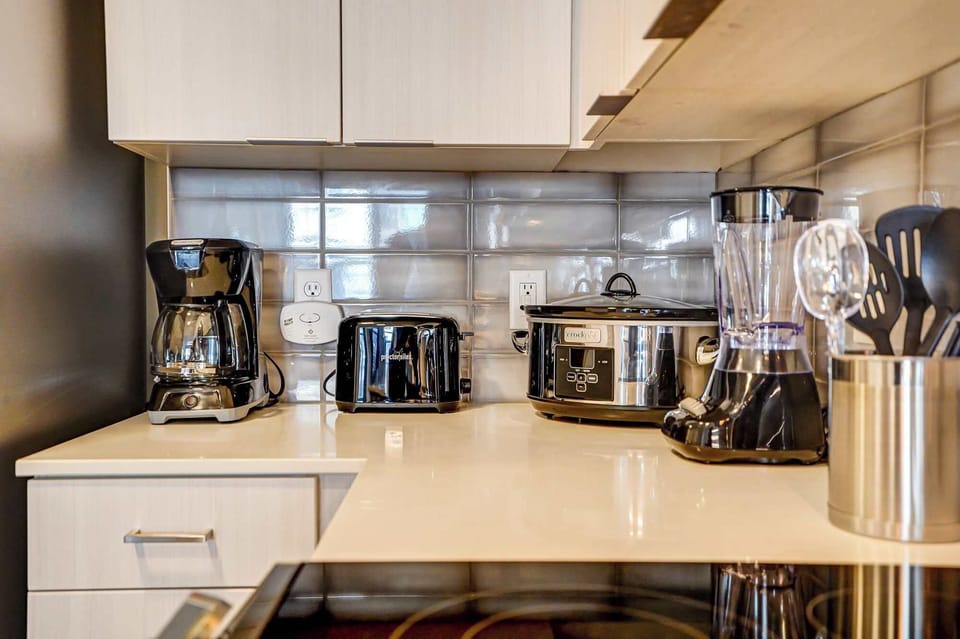 Coffee maker, toaster, slow cooker, and blender neatly arranged on the sleek kitchen counter, ready for your morning brew or a cozy home-cooked meal during your stay.