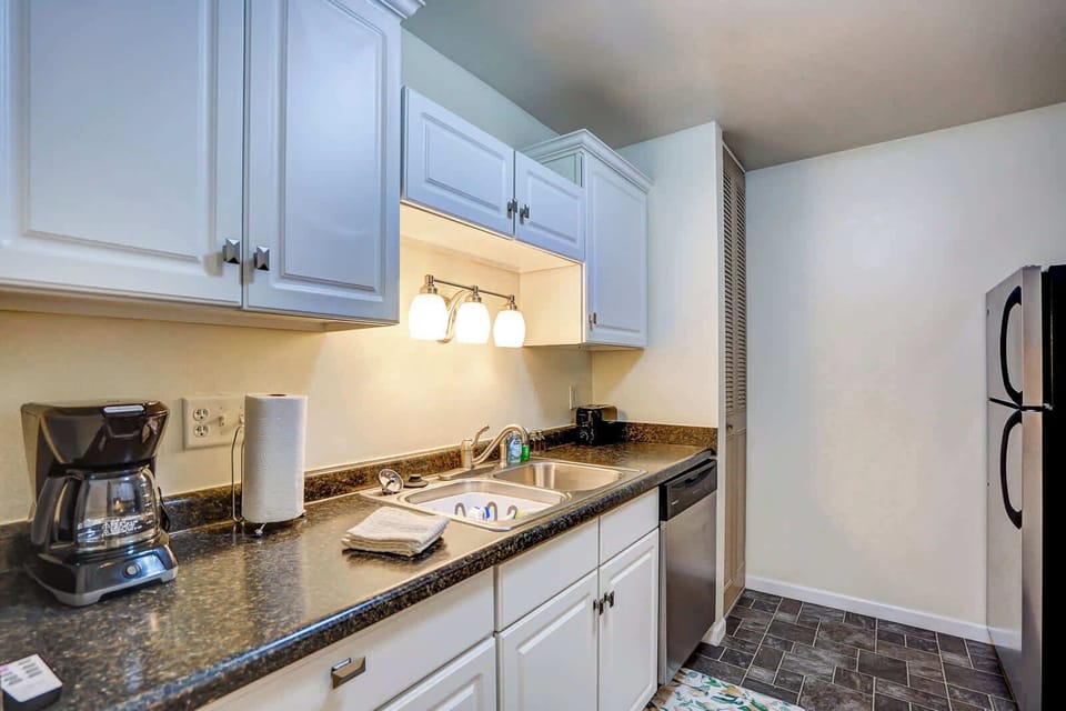 Sleek kitchen with stainless steel appliances, bright cabinetry, and modern lighting—fully equipped for effortless cooking and dining.