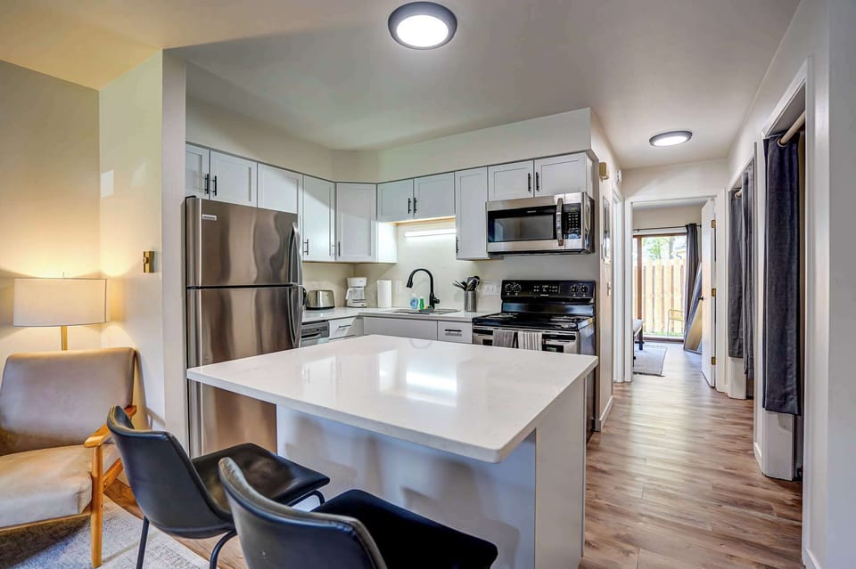 Bright modern kitchen with stainless steel appliances, white cabinetry, and a spacious island with seating—perfect for cooking or enjoying a meal together.