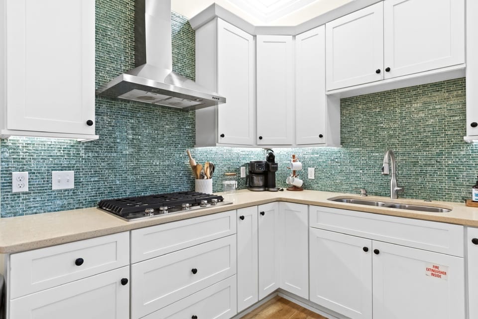 Bright modern kitchen with teal tile backsplash and stainless finishes