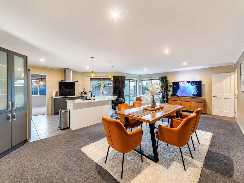 Spacious open-plan dining area with a large timber table, six chairs and easy access to the kitchen and living room.