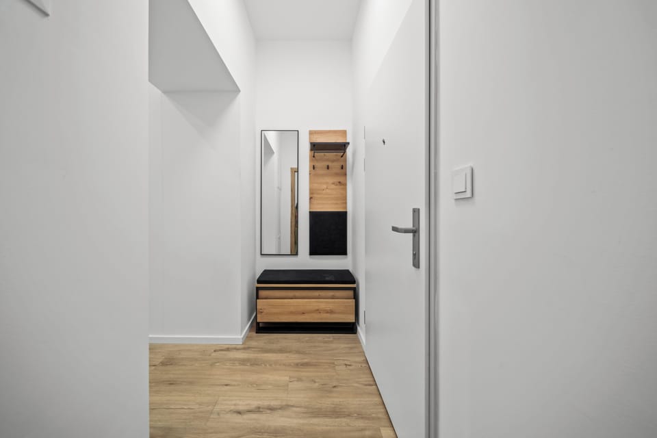 Bright modern entryway with bench seating, mirror, and convenient coat hooks