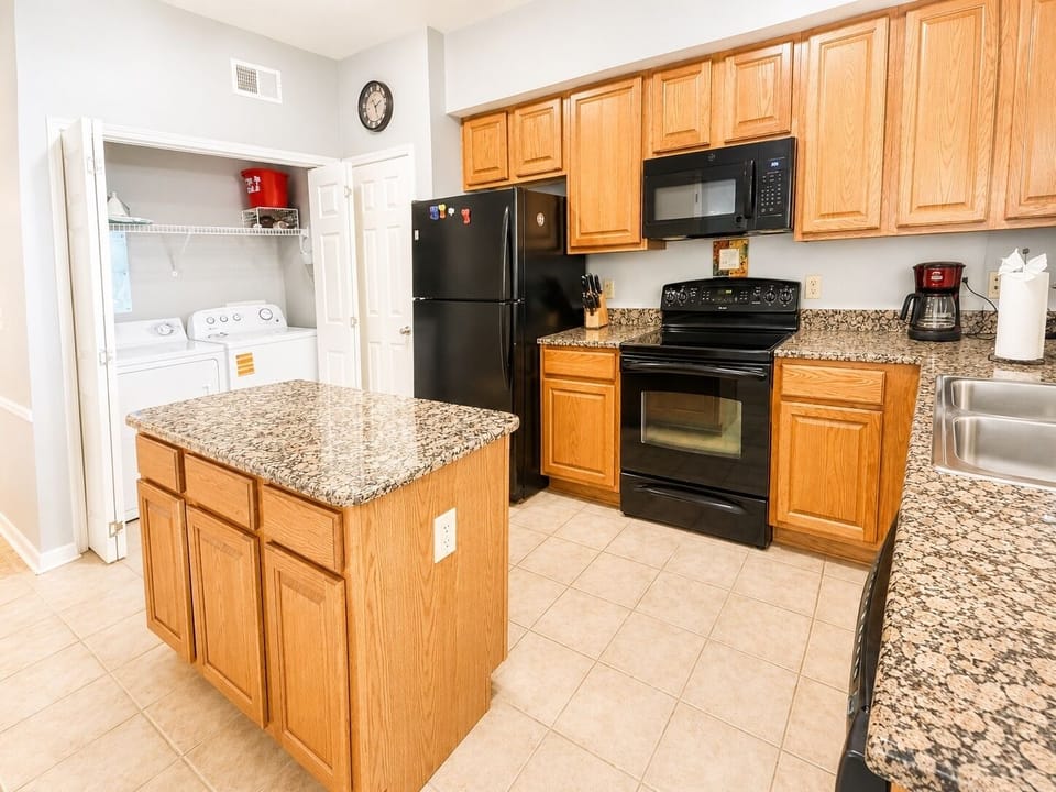 Fully Equipped Kitchen - A full kitchen with granite counters, island workspace, and convenient in-unit laundry nearby.