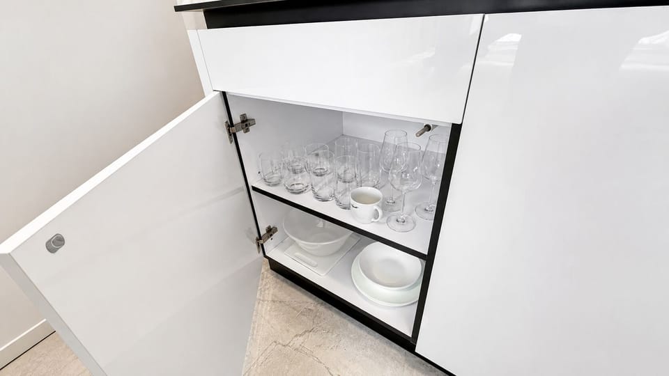 Modern kitchen storage stocked with glassware, dishes, and dining essentials