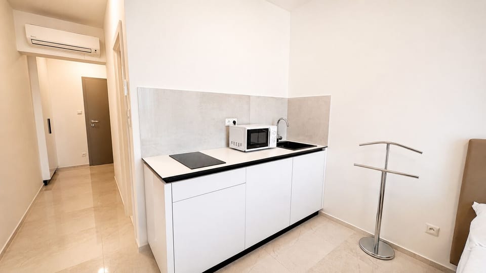 Bright modern kitchenette with cooktop, microwave, and sleek finishes