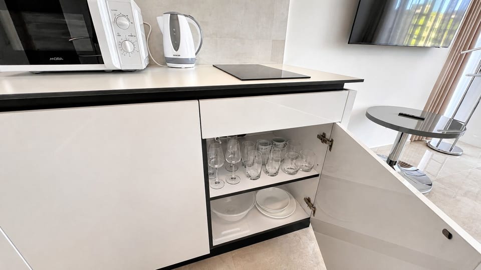 Modern kitchenette with stocked glassware, stovetop, and dining nook