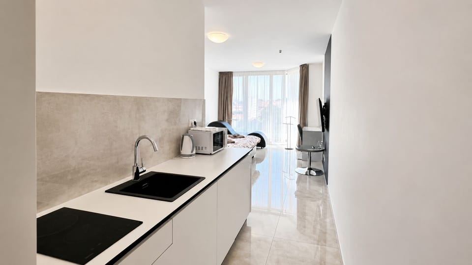 Bright modern studio with kitchenette, TV, and balcony access