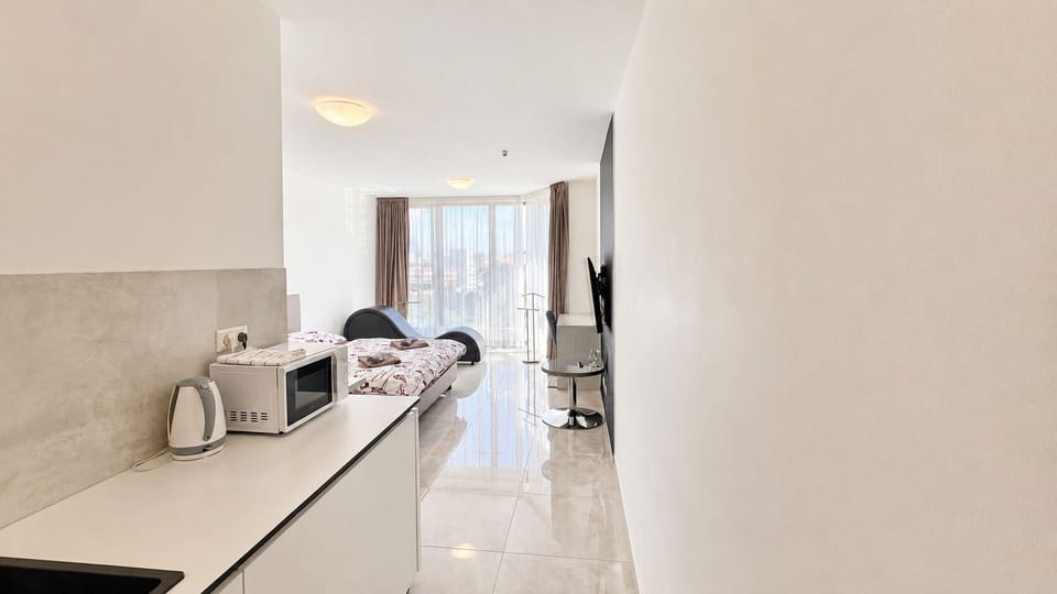 Bright studio with kitchenette, TV, and large windows with city views