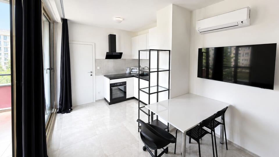 Bright modern kitchen-dining space with balcony, AC, and wall-mounted TV