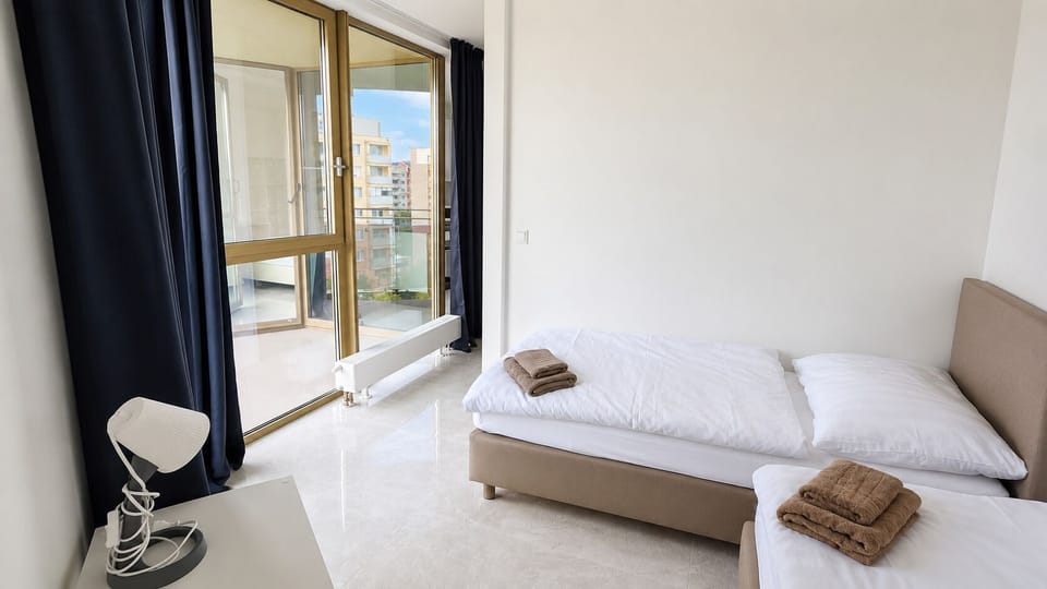 Bright twin bedroom with balcony access and city views