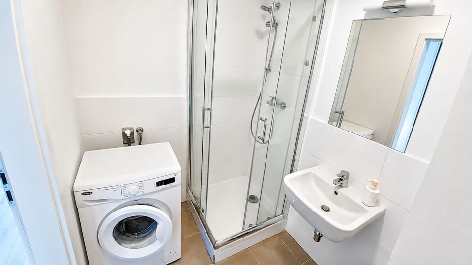 Modern bathroom with glass shower and in-unit washing machine