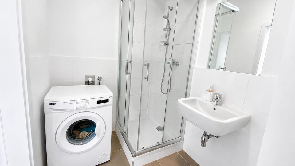 Bright modern bathroom with walk-in shower and in-unit washer