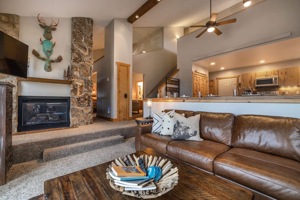 Sink into your comfortable leather sofa beside a crackling stone fireplace. Rustic charm meets modern comfort in this inviting open-concept space, with vaulted ceilings and a fully equipped kitchen ready for mountain getaways.