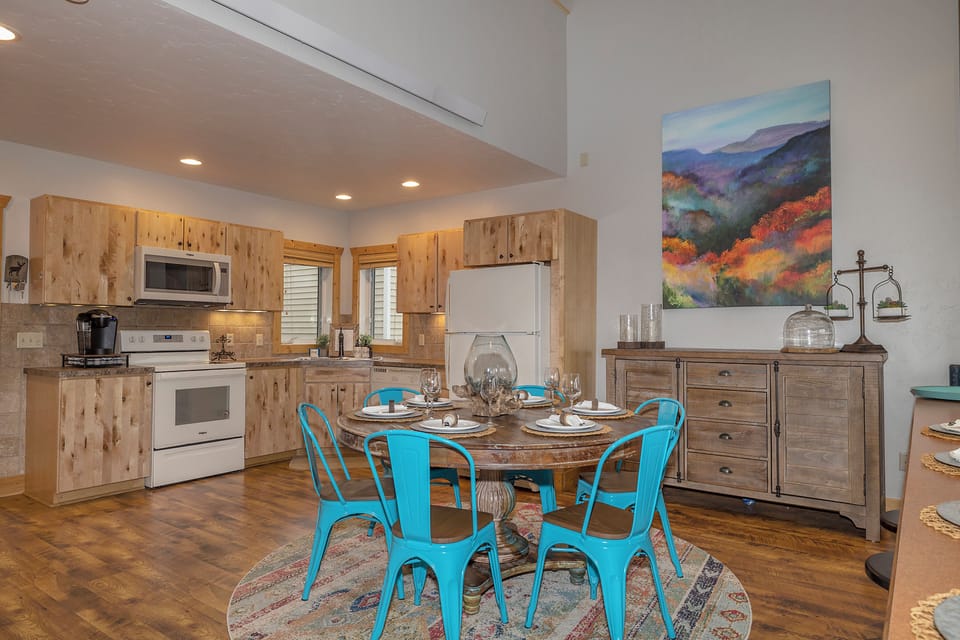 Gather around the rustic dining table for a relaxed meal in this open kitchen and dining space. Bright blue chairs add a cheerful touch, and natural wood tones create a warm, inviting atmosphere where you can cook and connect.
