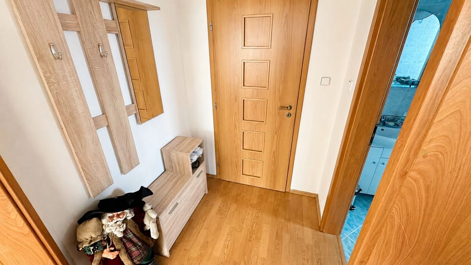 Bright entryway with coat hooks, storage bench, and bathroom access
