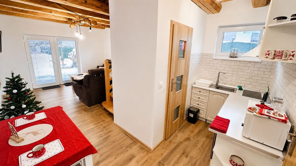 Charming open-plan space with rustic beams, bright kitchen, and patio access