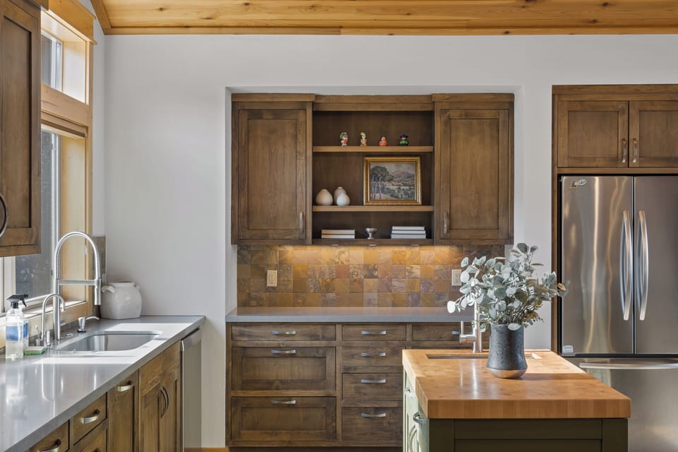 Warm wood cabinetry and natural stone accents create a welcoming kitchen where you can easily prepare meals and gather around the butcher-block island. Enjoy the bright natural light and rustic charm of this inviting space.