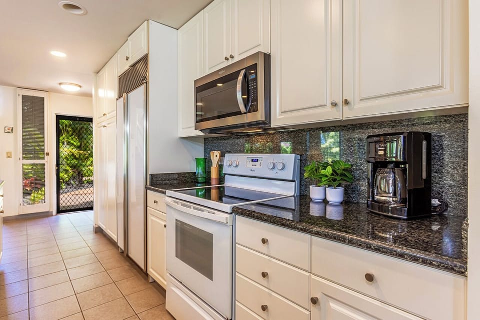 Your fully equipped kitchen has everything needed to prepare meals at home, from the sleek granite counters to the convenient microwave and coffee maker. Crisp white cabinetry and natural light create a welcoming space for cooking together.