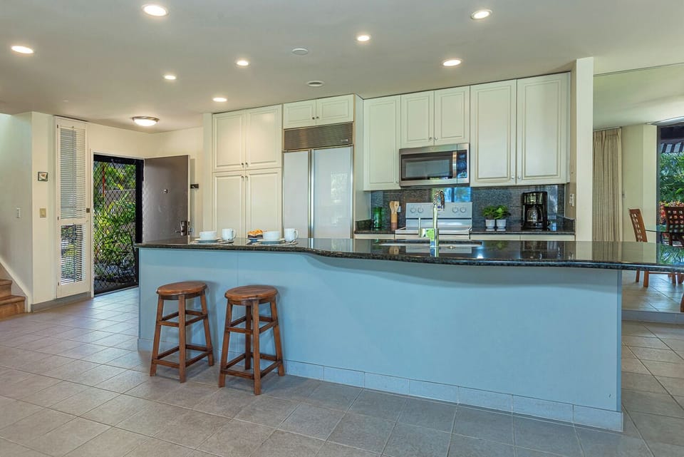 You'll love gathering in this bright, spacious kitchen with its sleek white cabinetry, generous granite counters, and central island with bar seating—perfect for morning coffee or evening meals.