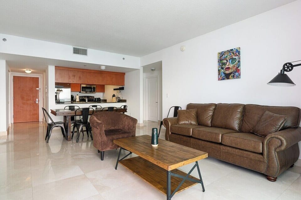 Open and inviting! This modern living space features a plush leather sofa, chic industrial-style furniture, and a seamless flow into the designer kitchen and dining area. Perfect for entertaining or relaxing in style.