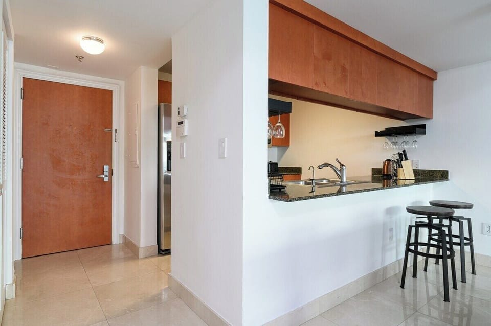 Sleek and functional! This modern kitchen features granite countertops, a built-in wine rack, and a convenient breakfast bar with stylish industrial stools. The open layout seamlessly connects the entryway to the heart of the home.