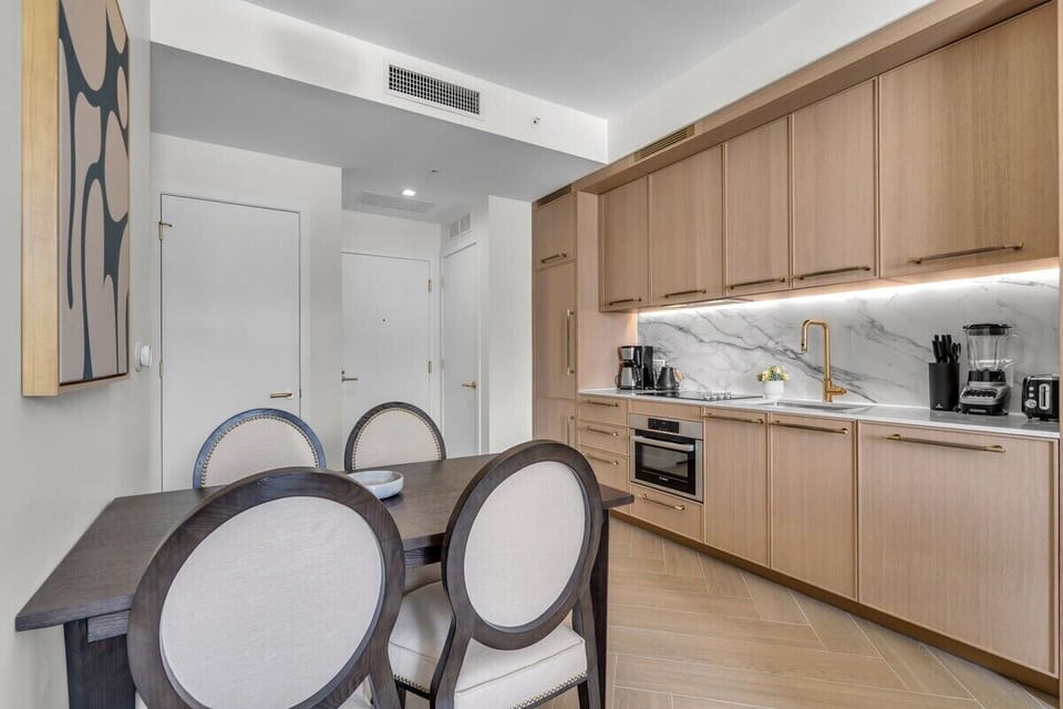 Elegant in-unit dining area with designer chairs, warm wood cabinetry and stylish pendant lighting — perfect for intimate meals at home