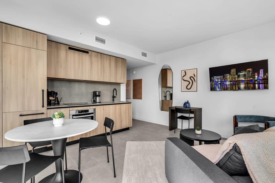 Modern open-concept living! This bright suite features a designer kitchen with seamless wood cabinetry, a stylish dining area, and a cozy lounge. Floor-to-ceiling windows offer stunning city views in a sleek, minimalist space.