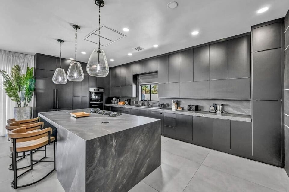 Gather in the stunning open-concept kitchen, featuring high-end finishes, designer décor, premium appliances, and a sleek cooktop built directly into the oversized island.