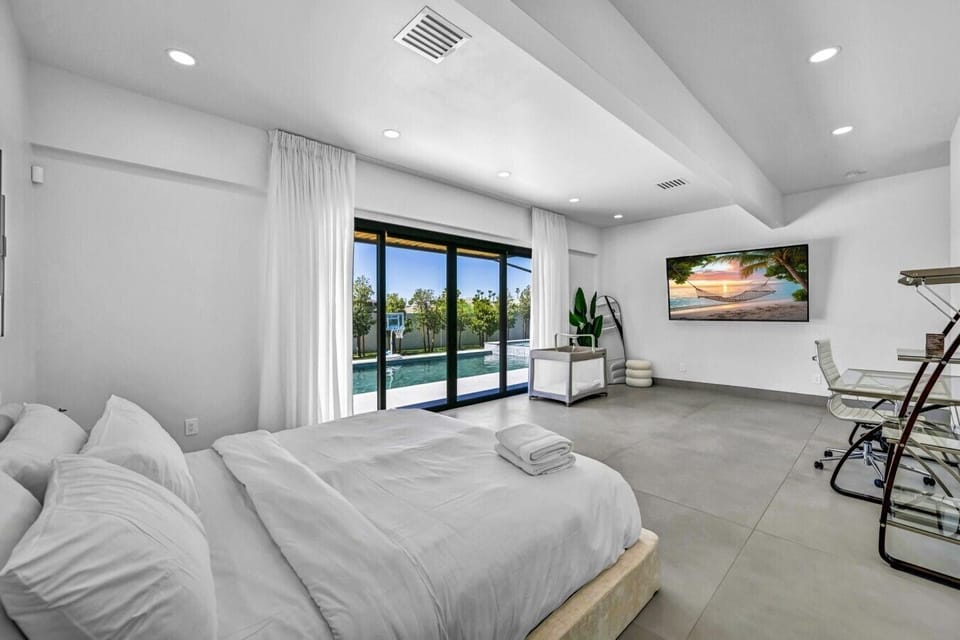 Wind down in the luxurious primary suite, featuring cozy textures, calming tones, a spacious walk-in closet, private pool and patio access, plus a high-end bathroom with a soaking tub and oversized rain shower.