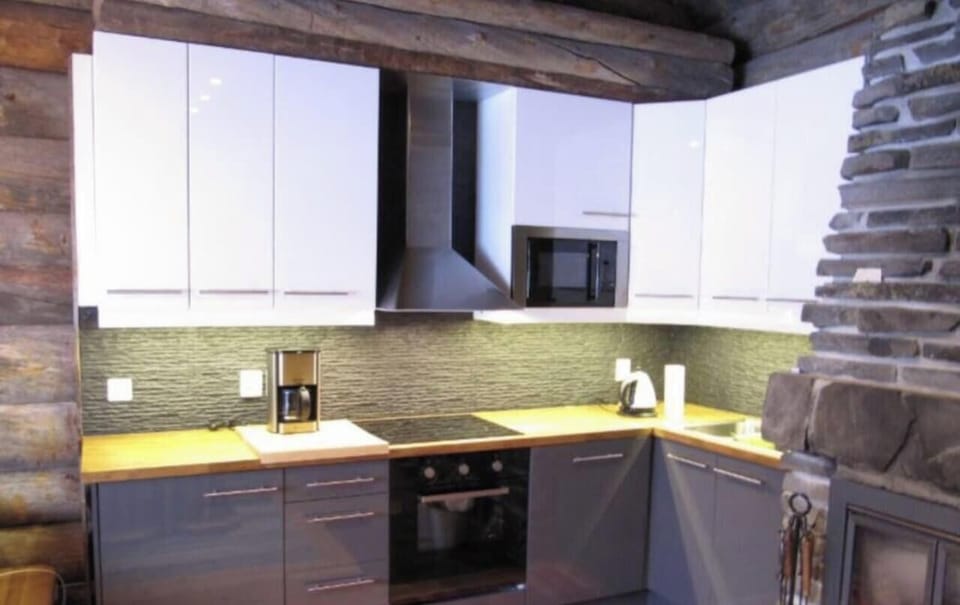 Modern kitchen with an oven, microwave, coffee maker and kettle on a wooden worktop.