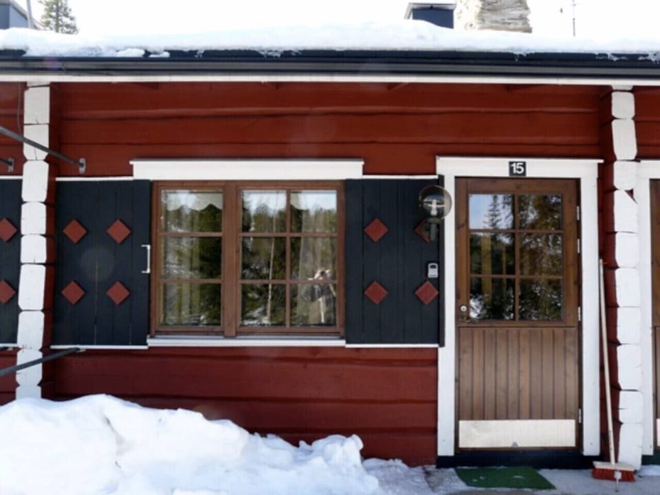 Red log building exterior with its own entrance in a snowy winter setting.
