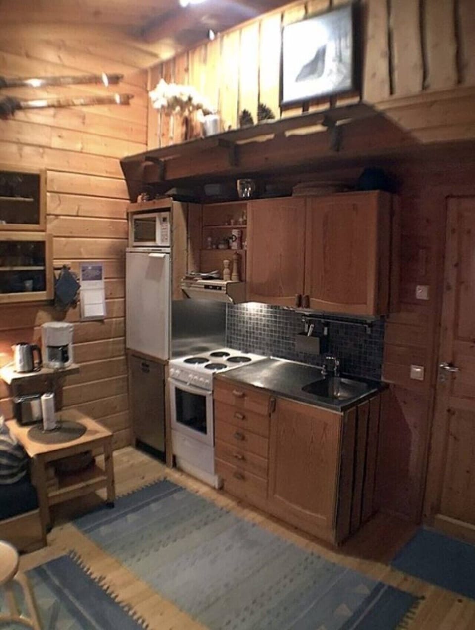 Wooden kitchen with an electric stove, oven, refrigerator, microwave and coffee maker.