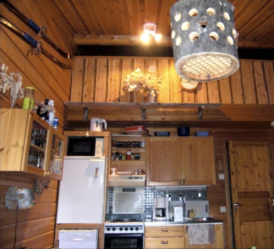 Kitchen with a refrigerator and microwave beneath the open loft space.