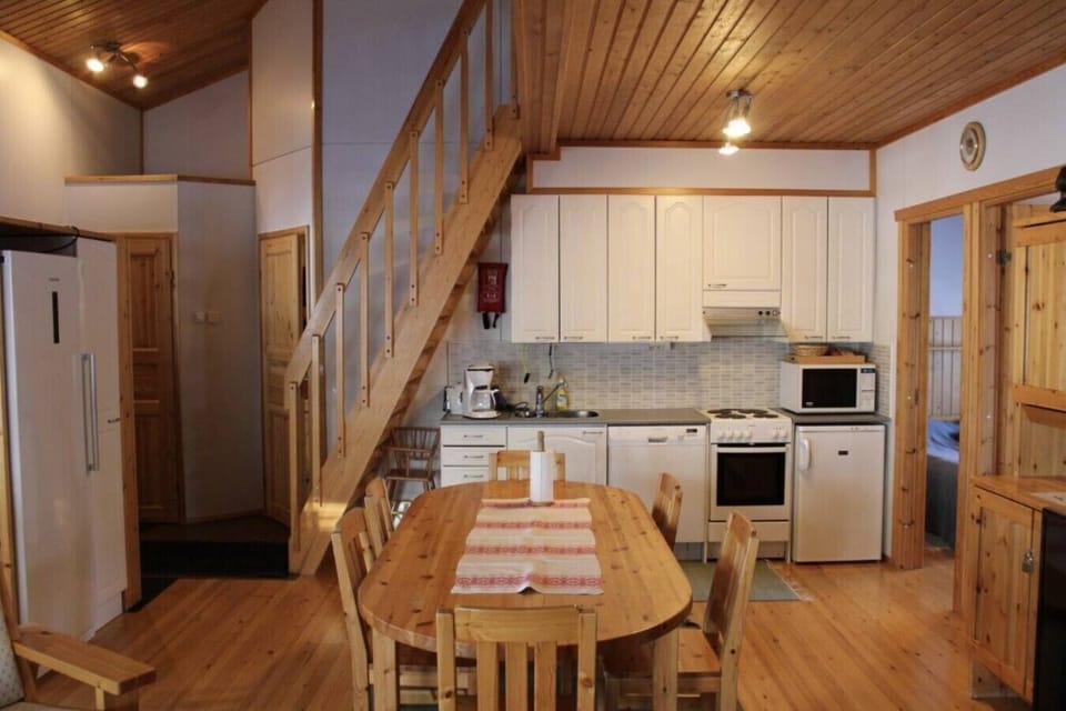 Kitchen with a refrigerator, oven, microwave and a wooden dining table.
